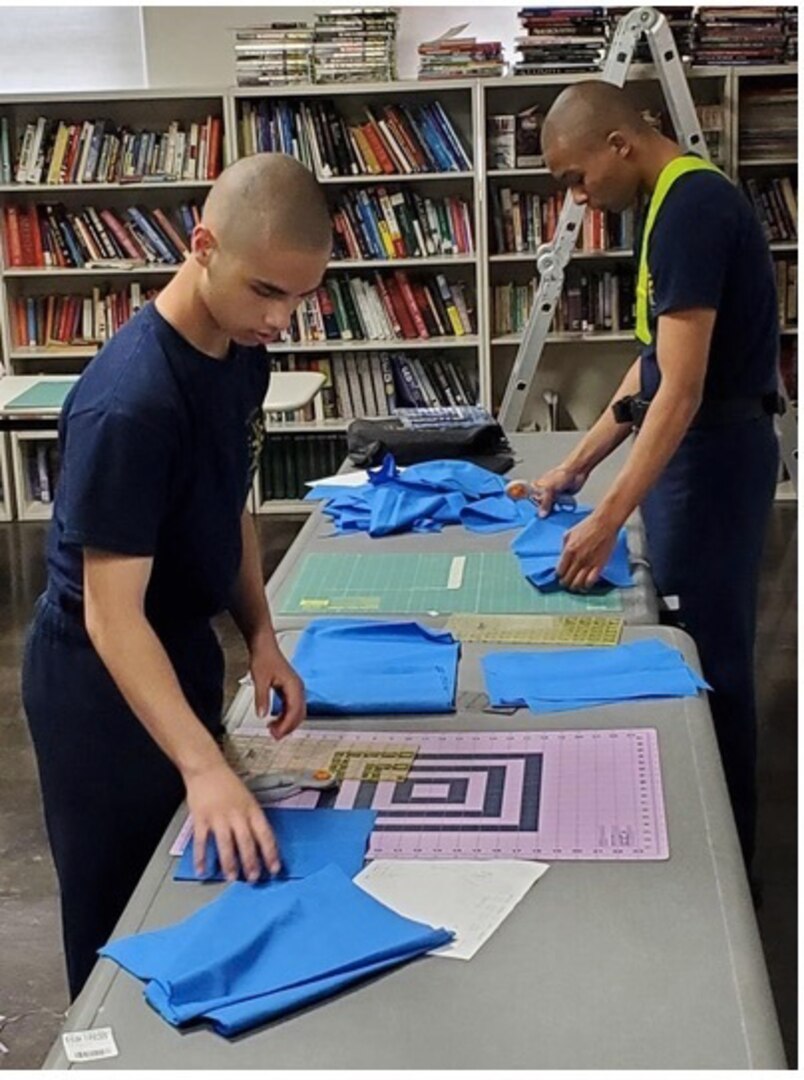 Michigan Youth Challenge Academy Cadets Jonathan Ciszczon and Jonathan Shapiro measure and cut fabric to make cloth masks to be donated to facilities in the Battle Creek community April 8, 2020.