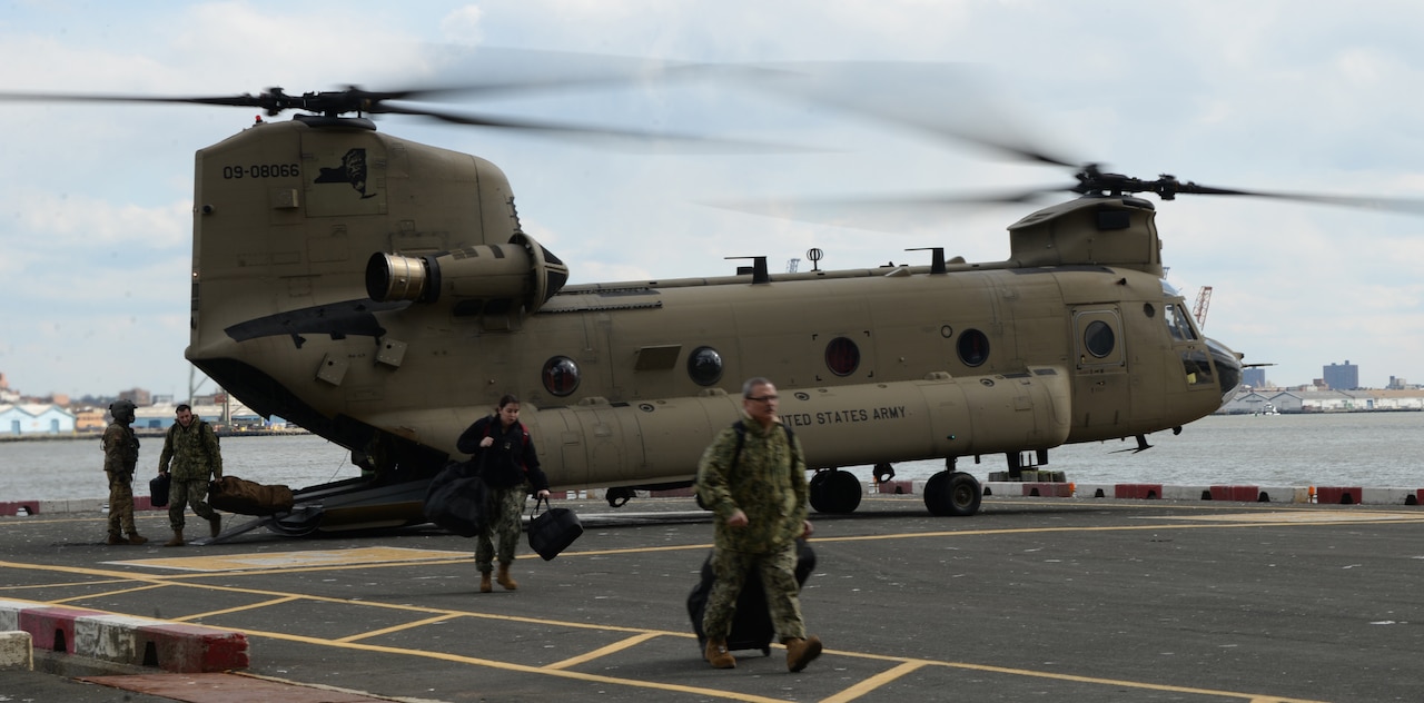 Crew members walk away from a helicopter after landing.