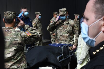 New York Army National Guard Sgt. Major Nicholas Pardi, a member of the 104th Military Police Battalion, presents an American flag during an impromptu memorial service for a  veteran who died of COVID-19 while a patient at the Javits New York Medical Station in the Jacob Javits Convention Center in New York City, April 19, 2020.