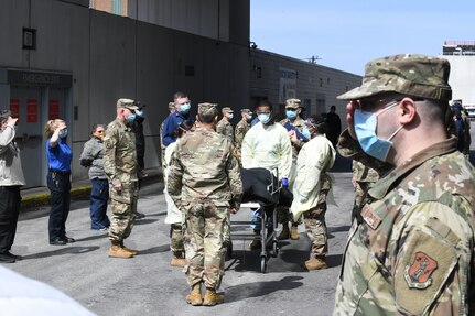 Military members and civilians working at the Javits New York Medical Station in New York City render military honors April 19, 2020, to a veteran who died of COVID-19 while a patient at the medical station.