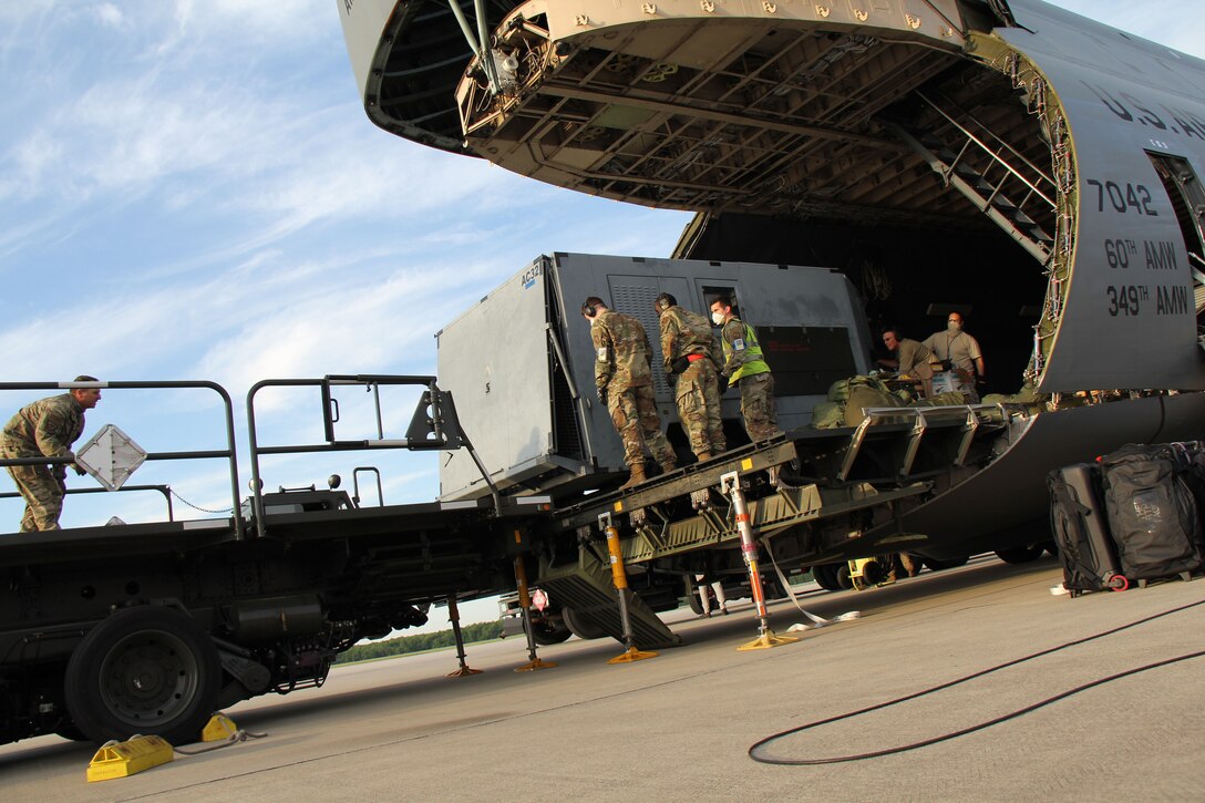 Photo shows uniformed members loading cargo from a C-5 Galaxy aircraft to the back of a truck.