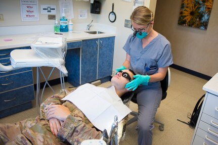 Maj. Leslie Chambers, a general dentist assigned to the 628th Operational Medical Readiness Squadron, performs a deployment exam on Senior Airman Garrett Ropon, an electrical power production journeyman assigned to the 628th Civil Engineering Squadron at Joint Base Charleston, S.C., April 21, 2020. The dental clinic is open for dental emergencies and deployment exams. Dental clinic personnel are protecting their patients and themselves by regularly cleaning surfaces, wearing masks and gloves, reducing the number of patients they see, practicing physical distancing whenever possible and having patients use pretreatment mouth rinse. (U.S. Air Force photo by Airman Sara Jenkins)