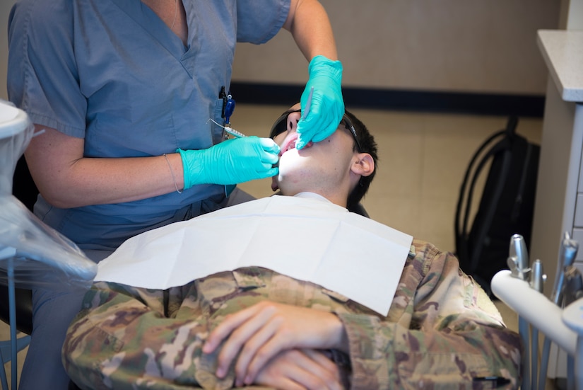 Maj. Leslie Chambers, a general dentist assigned to the 628th Operational Medical Readiness Squadron, performs a deployment exam on Senior Airman Garrett Ropon, an electrical power production journeyman assigned to the 628th Civil Engineering Squadron at Joint Base Charleston, S.C., April 21, 2020. The dental clinic is open for dental emergencies and deployment exams. Dental clinic personnel are protecting their patients and themselves by regularly cleaning surfaces, wearing masks and gloves, reducing the number of patients they see, practicing physical distancing whenever possible and having patients use pretreatment mouth rinse. (U.S. Air Force photo by Airman Sara Jenkins)