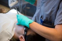 Maj. Leslie Chambers, a general dentist assigned to the 628th Operational Medical Readiness Squadron, performs a deployment exam on Senior Airman Garrett Ropon, an electrical power production journeyman assigned to the 628th Civil Engineering Squadron at Joint Base Charleston, S.C., April 21, 2020. The dental clinic is open for dental emergencies and deployment exams. Dental clinic personnel are protecting their patients and themselves by regularly cleaning surfaces, wearing masks and gloves, reducing the number of patients they see, practicing physical distancing whenever possible and having patients use pretreatment mouth rinse. (U.S. Air Force photo by Airman Sara Jenkins)
