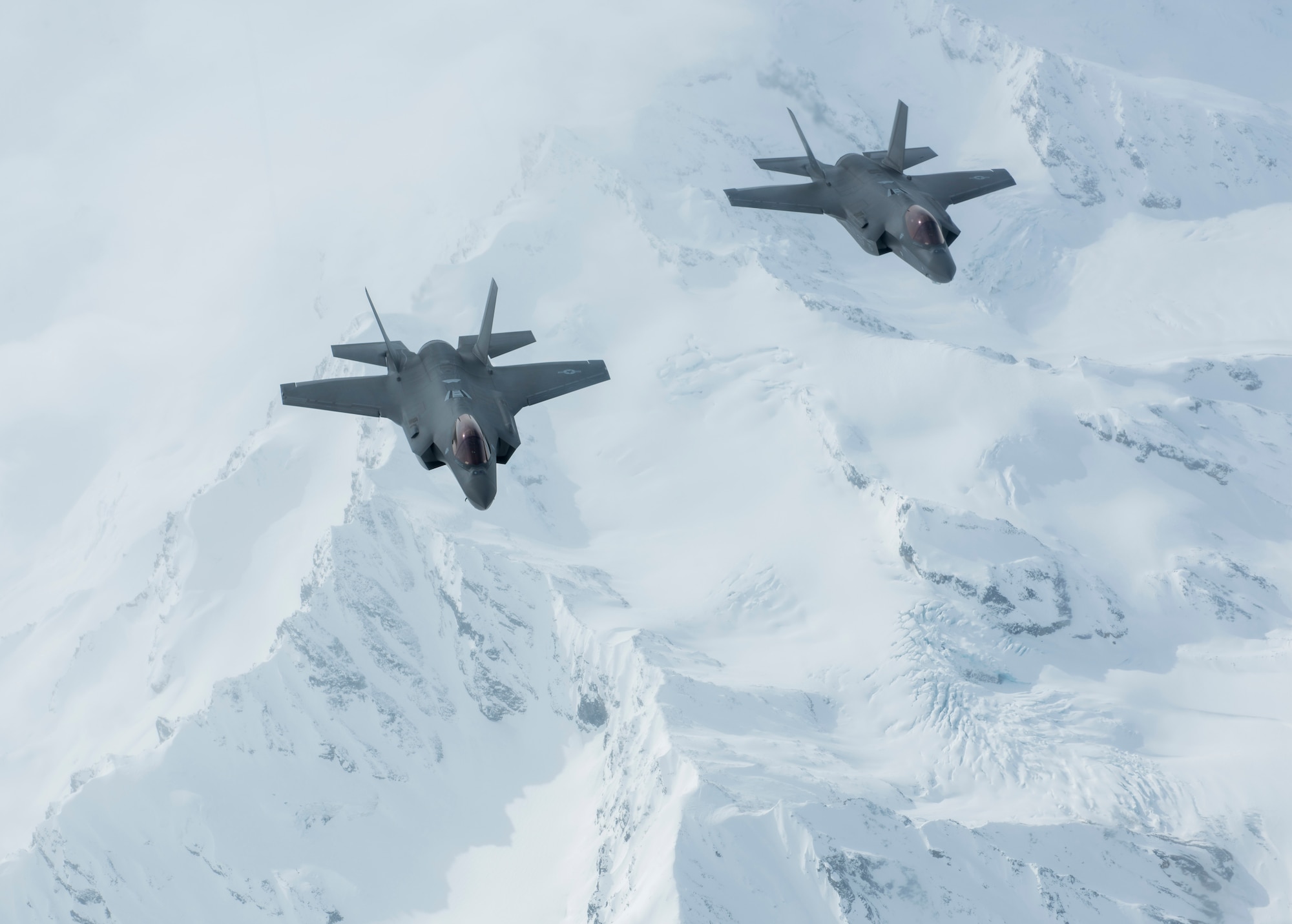 Two F-35A Lightning II aircraft fly over the Alaska Range en route to their new home at the 354th Fighter Wing, Eielson Air Force Base, Alaska, April 21, 2020.