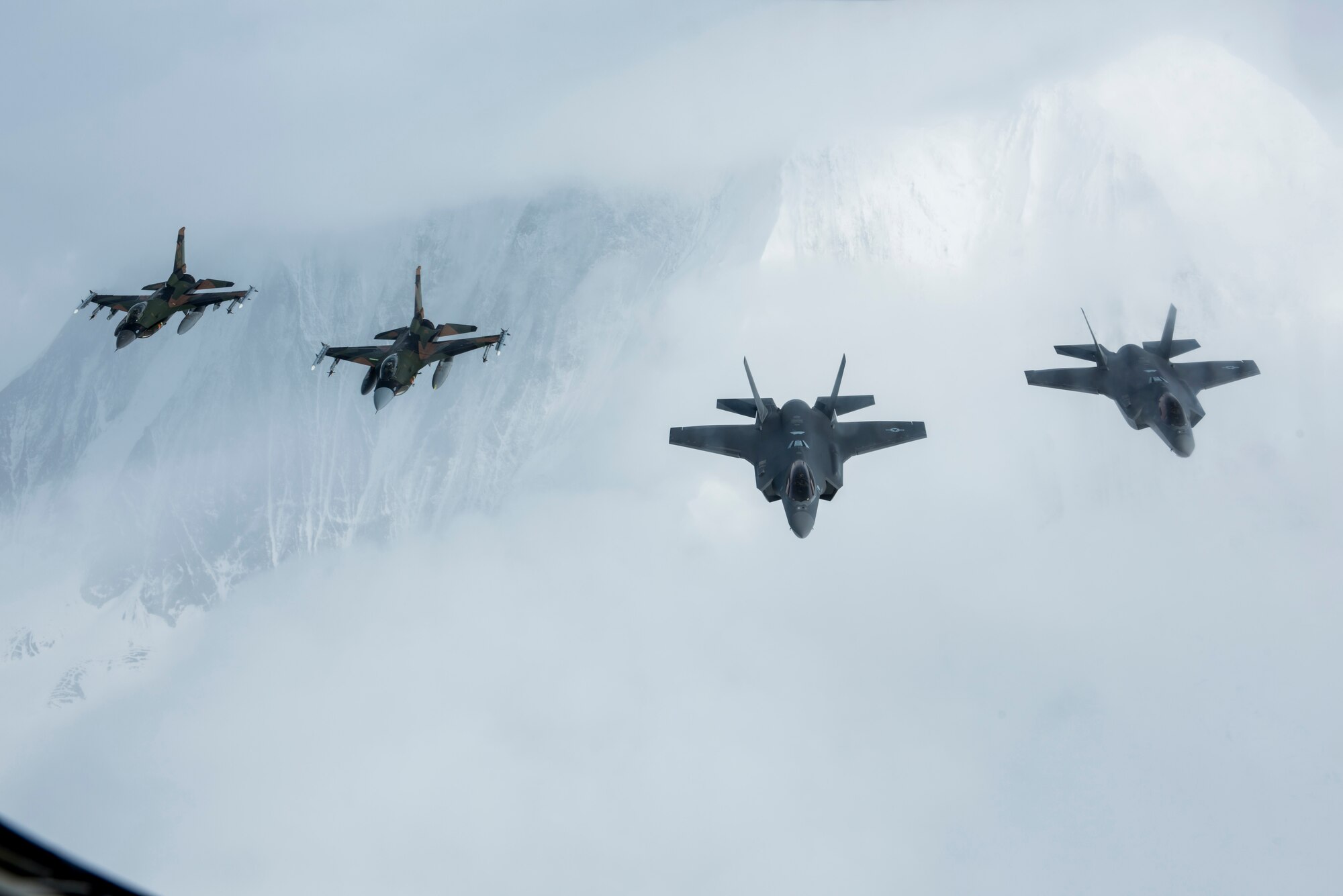 Two F-16C Fighting Falcons and two F-35A Lightning IIs from the 354th Fighter Wing, Eielson Air Force Base, Alaska, fly in formation behind a KC-135R Stratotanker from the 168th Wing, Alaska Air National Guard, Eielson AFB, over the Alaska Range, April 21, 2020.