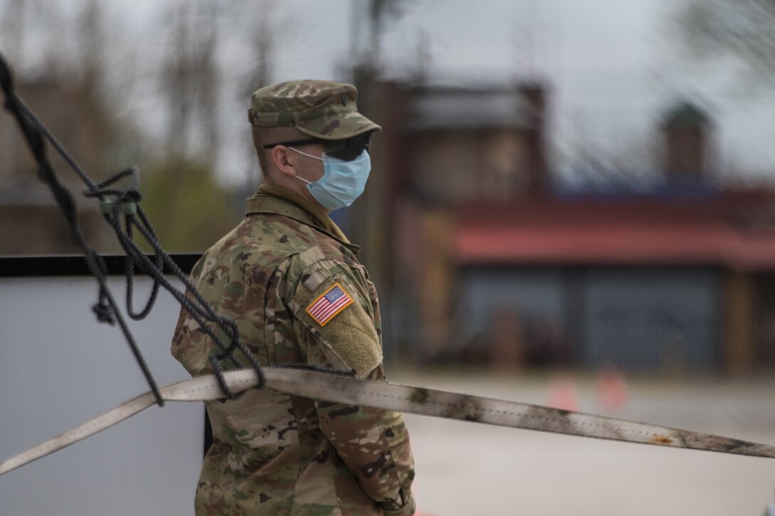 Soldier stands wearing a face mask.