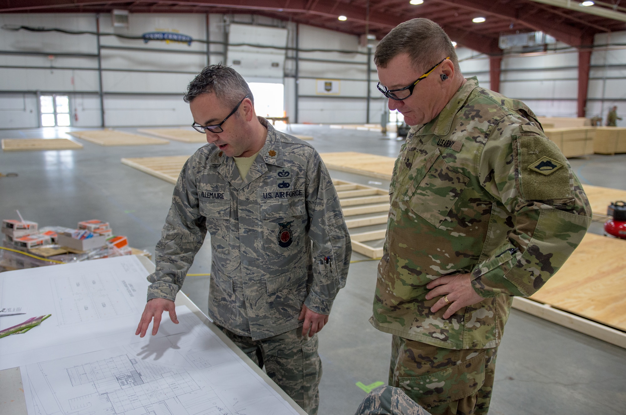 Maj. Jason Villemaire, a civil engineer assigned to the 158th Mission Support Group, Vermont Air National Guard, presents Army Brig. Gen. Gregory Knight, the adjutant general of the Vermont National Guard, with the floor plans for the construction of a 400-bed medical health facility at the Champlain Valley Exposition.