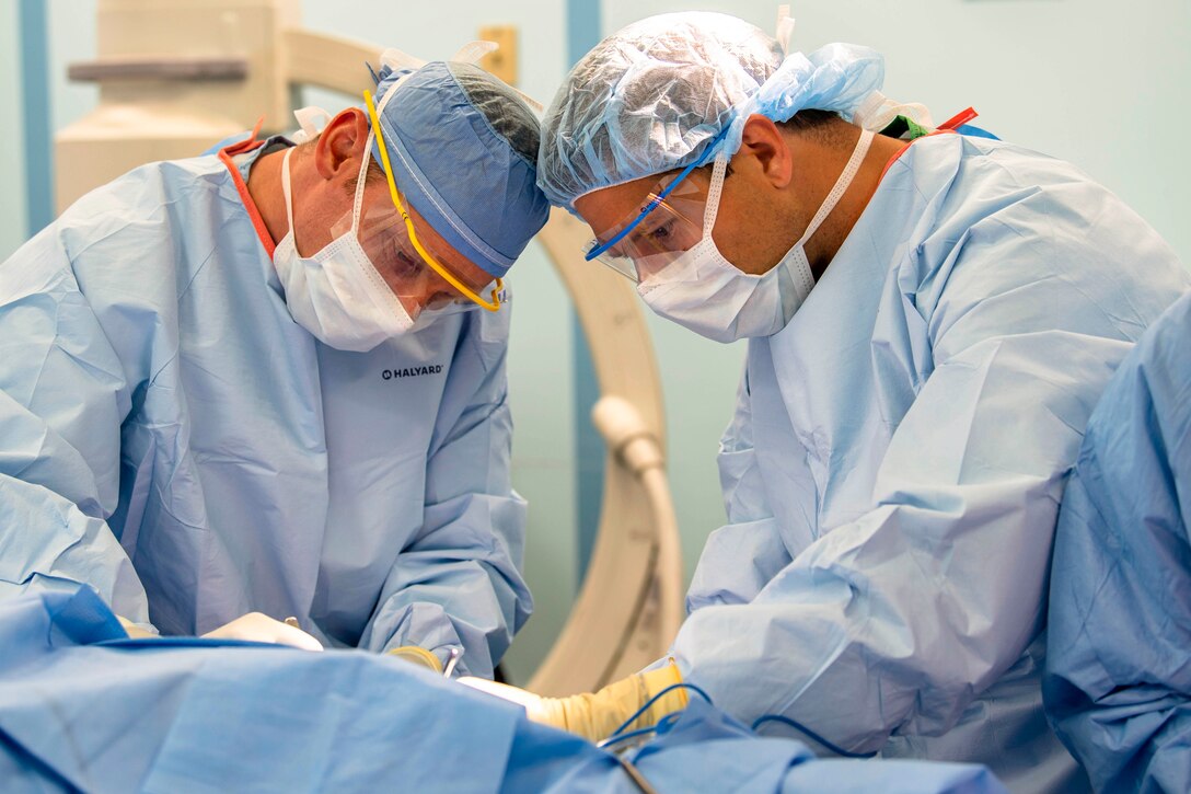 Sailors perform a surgery on a patient.