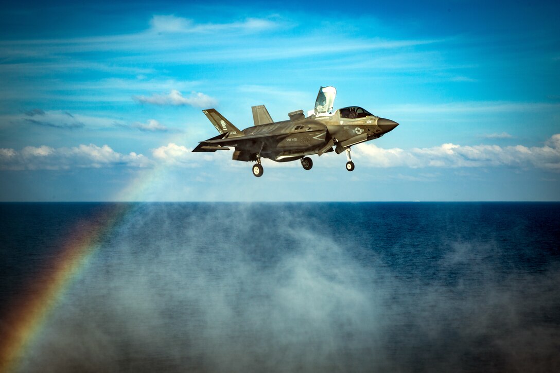 A rainbow shines behind a plane preparing to land.