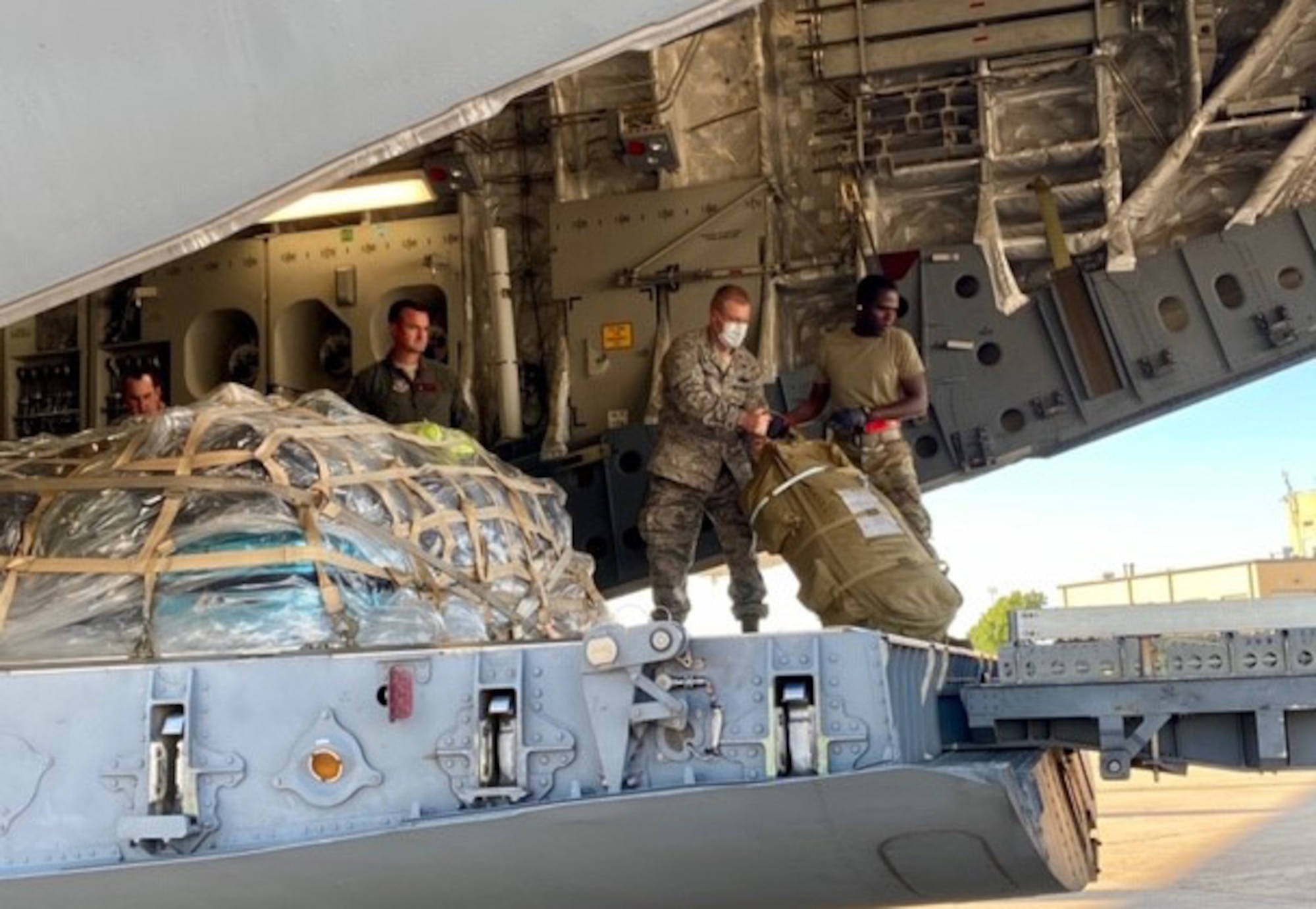 301st Fighter Wing Commander, Col. Allen Duckworth, second from right, helps to load luggage of deploying Airmen aboard a C-17 Globemaster III at U.S. Naval Air Station Joint Reserve Base, Fort Worth, Texas on April 22, 2020. This deployment is part of a larger mobilization package of more than 770 Air Force Reservists from across the nation who are taking care of Americans fighting COVID-19. (U.S. Air Force photo by Capt. Jessica Gross)