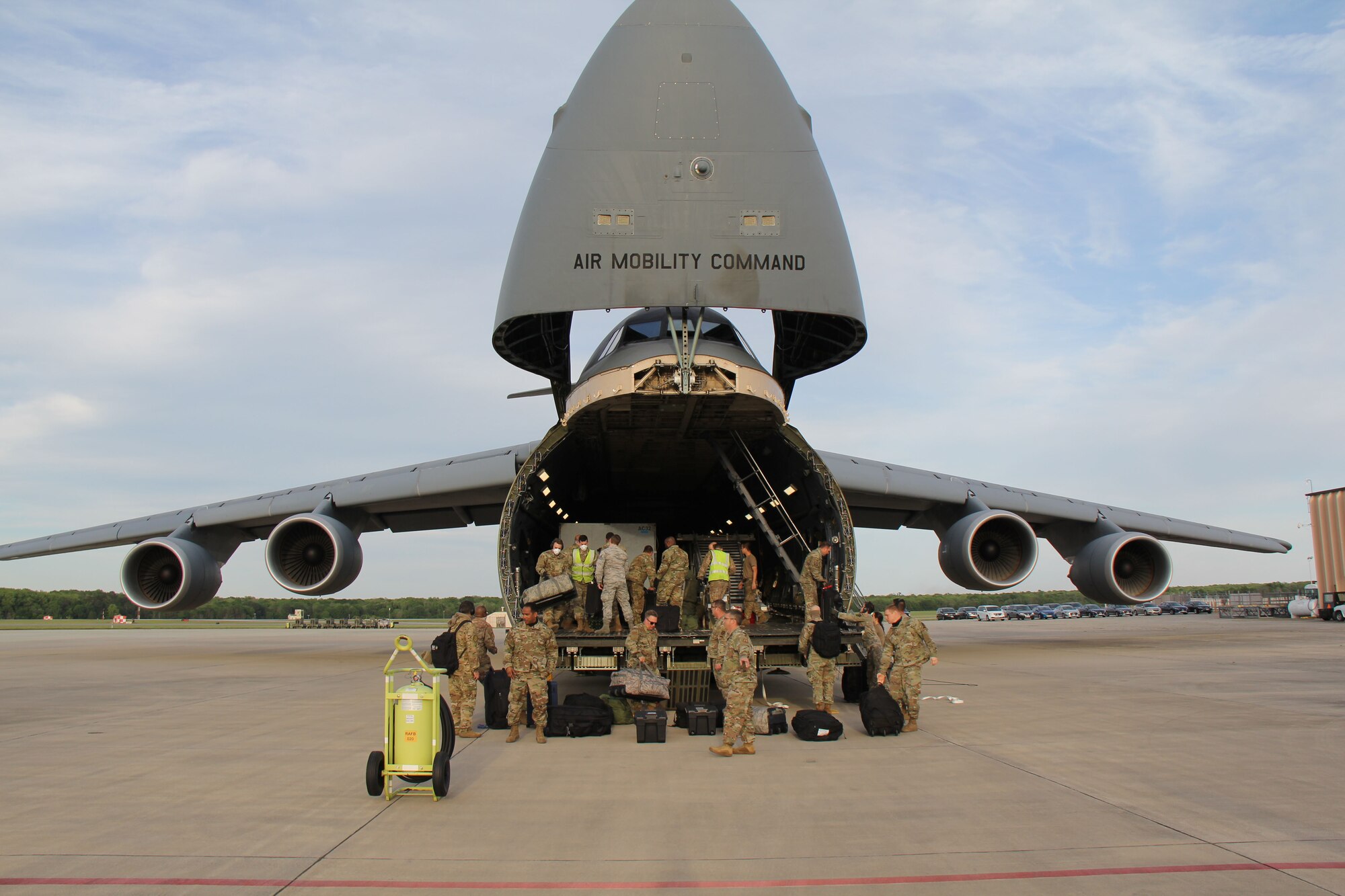 Photo shows uniformed members unloading cargo from the front end of a C-5 Galaxy aircraft.