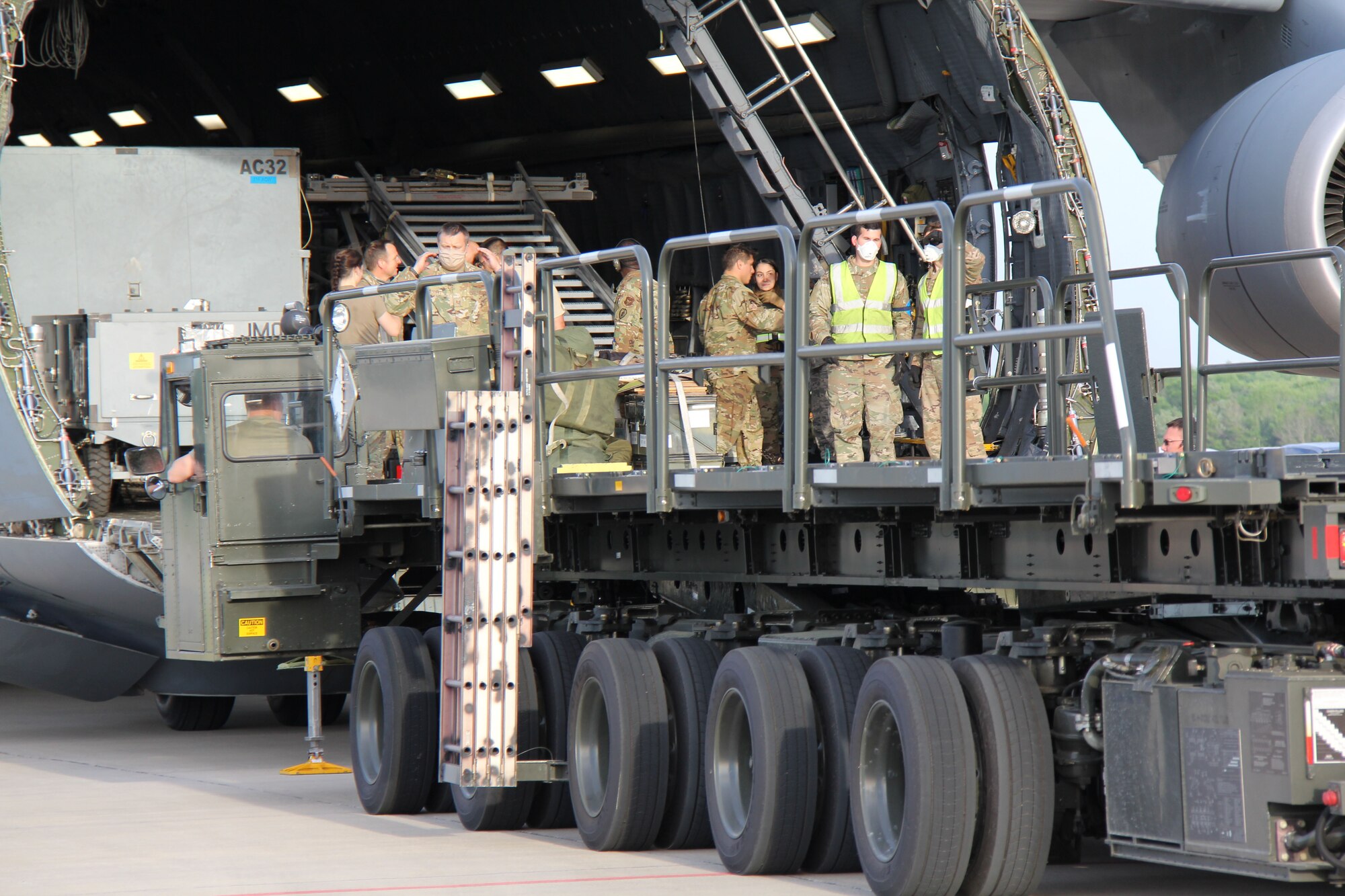 Photo shows uniformed members unloading cargo from the front end of a C-5 Galaxy aircraft.