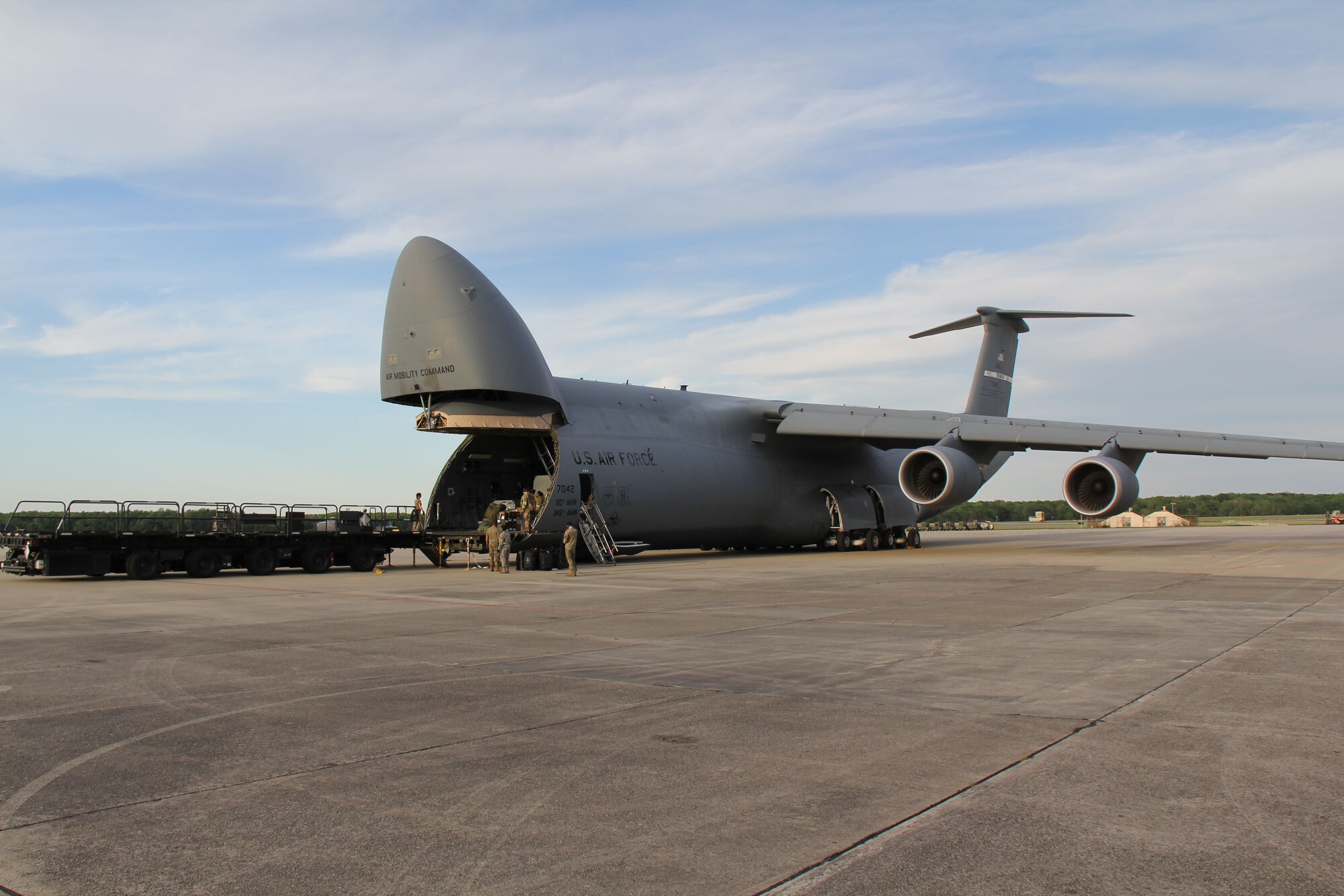 Photo shows uniformed members unloading cargo from the front end of a C-5 Galaxy aircraft.