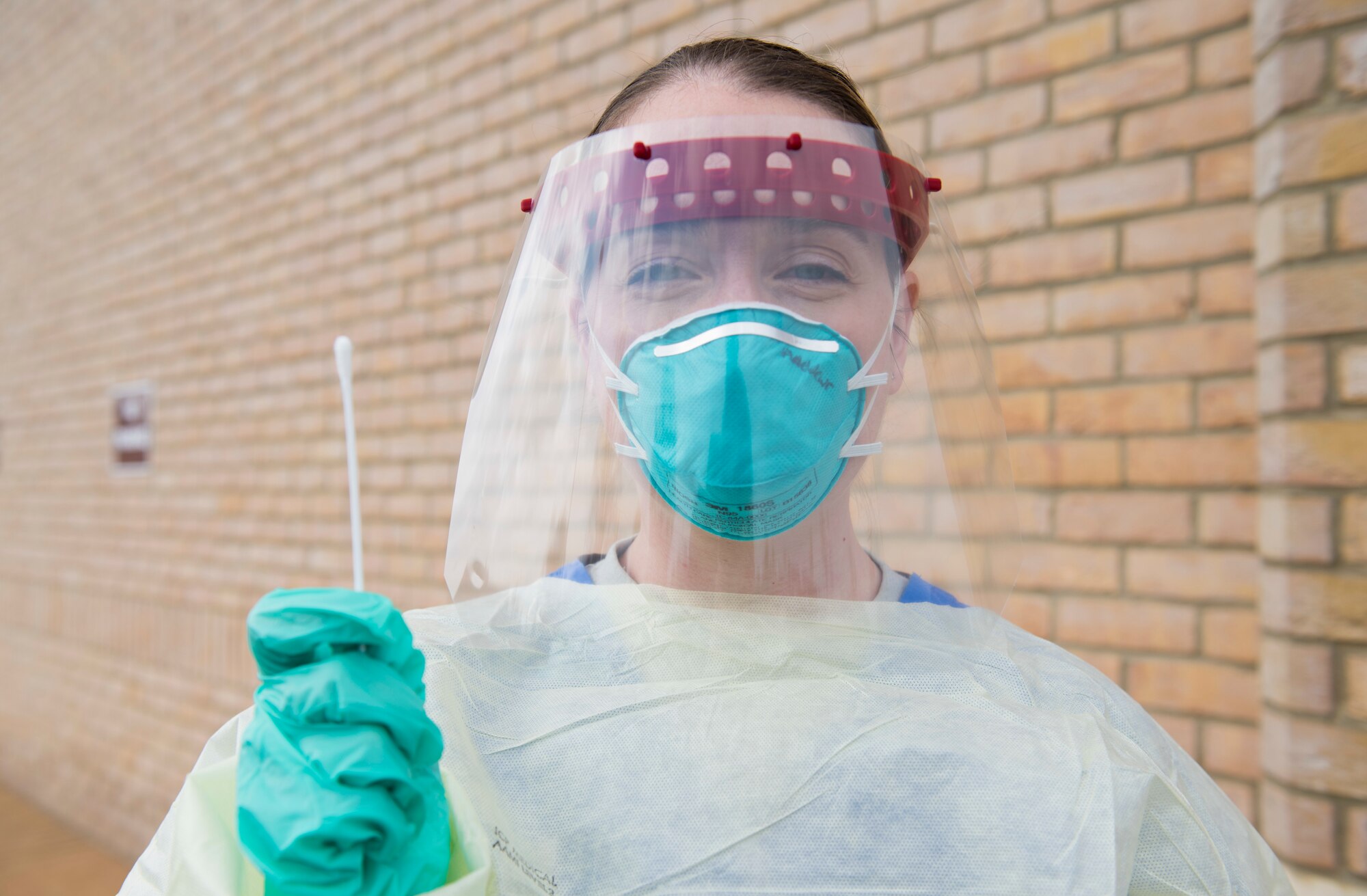 U.S. Air Force Capt. Jennifer Andrews, 423rd Medical Squadron family health clinic element chief, clinical nurse and infection preventionist, poses for a photo in a 3-D face shield as she holds a swab at a COVID-19 drive-up testing station at RAF Alconbury, England, April 13, 2020. The 423rd MDS transformed their parking lot into a drive-thru to expedite testing and prevent the spread of COVID-19. (U.S. Air Force photo by Airman 1st Class Jennifer Zima)