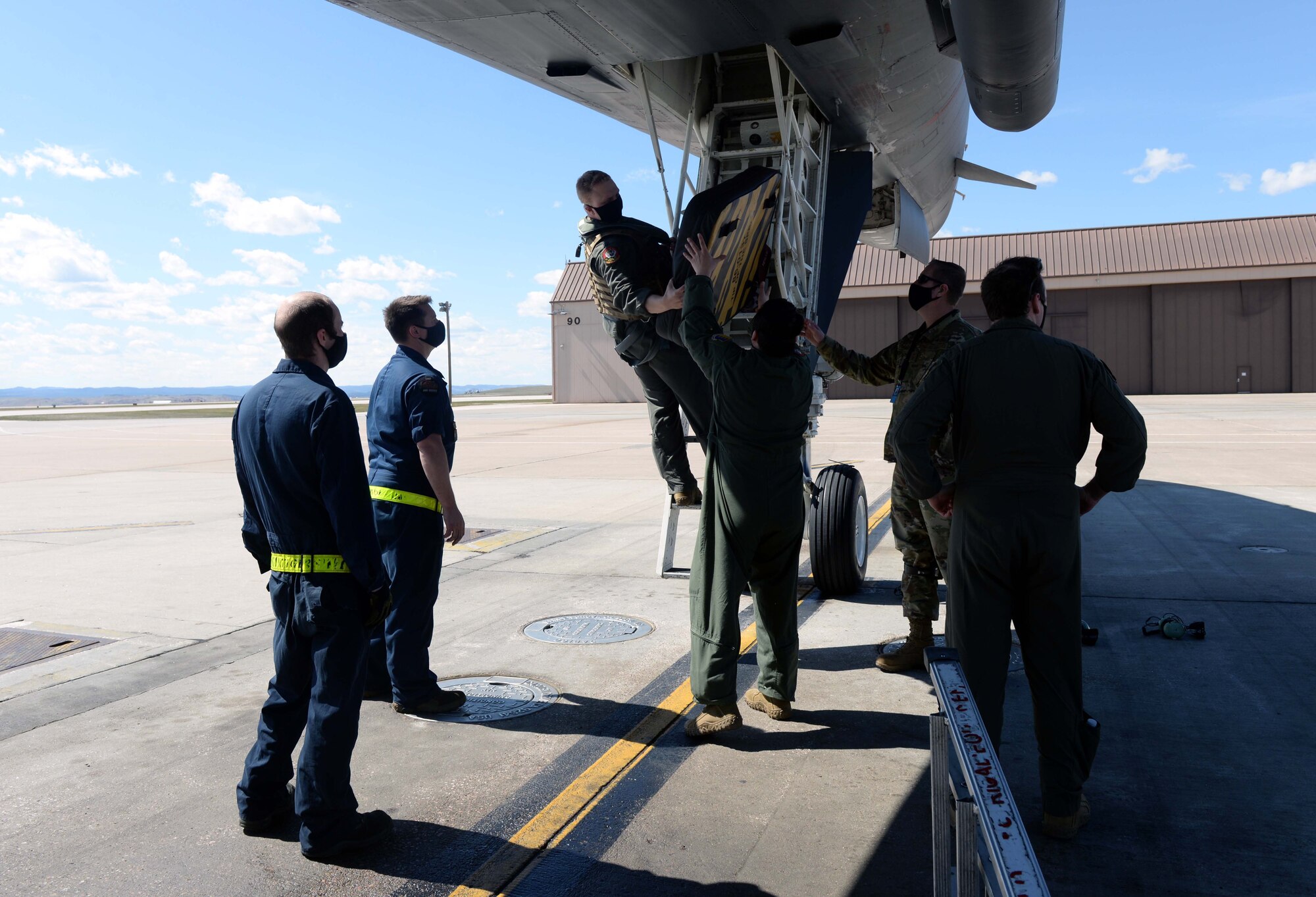 An aircrew member passes off the engine covering of a B-1B Lancer to maintainers assigned to the 28th Aircraft Maintenance Squadron at Ellsworth Air Force Base, S.D., April 22, 2020.