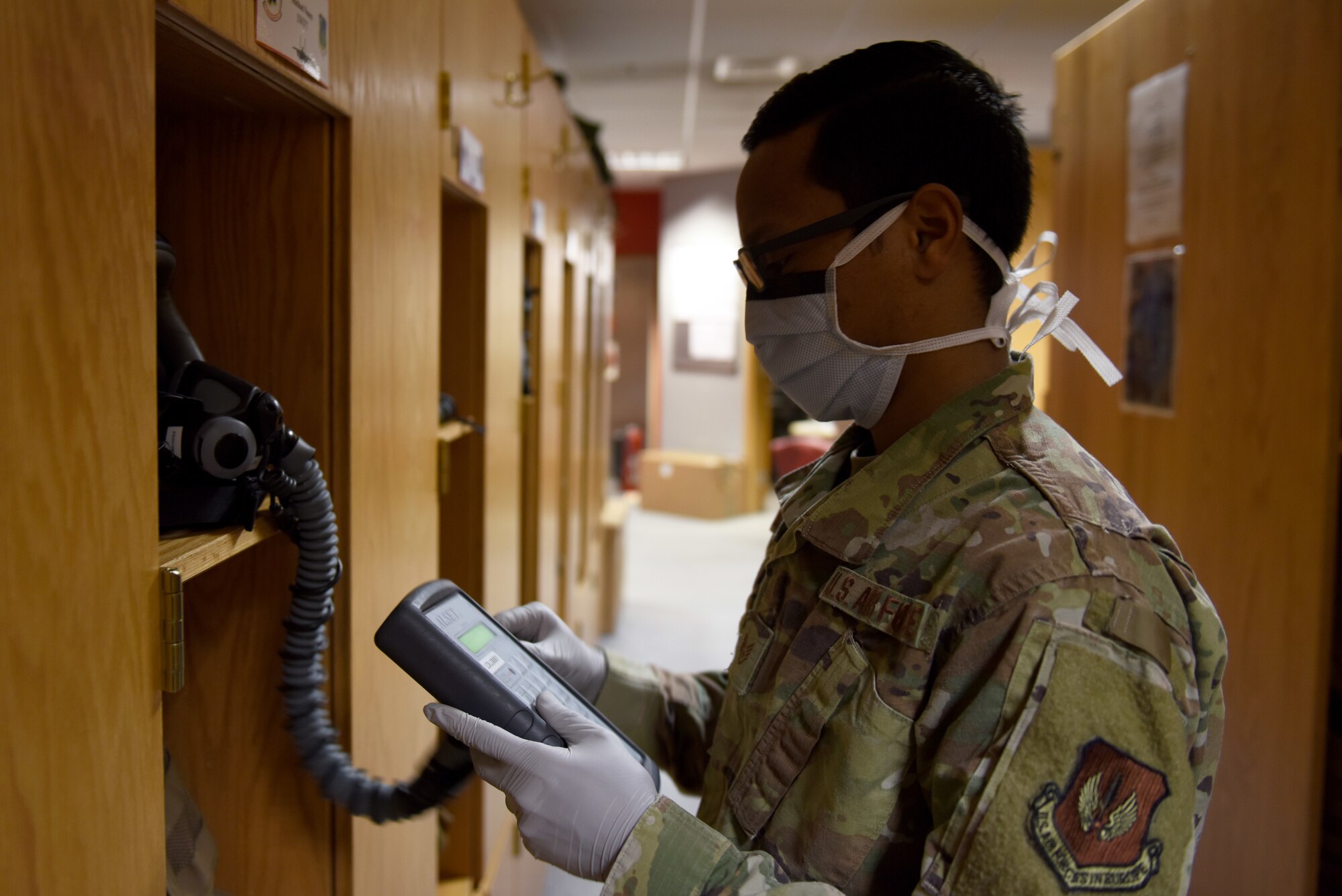 An Aircrew Flight Equipment Airman assigned to 494th Fighter Squadron checks flight gear at Royal Air Force Lakenheath, England, April 22, 2020. AFE technicians wear personal protective equipment such as masks and gloves while supporting continued mission operations despite the COVID-19 pandemic. (U.S. Air Force photo by Airman 1st Class Rhonda Smith)