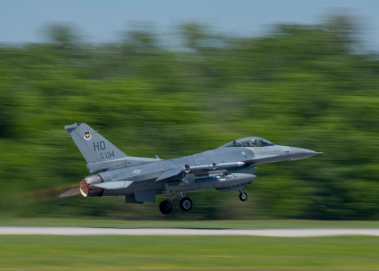 plane taking off from runway with trees in background