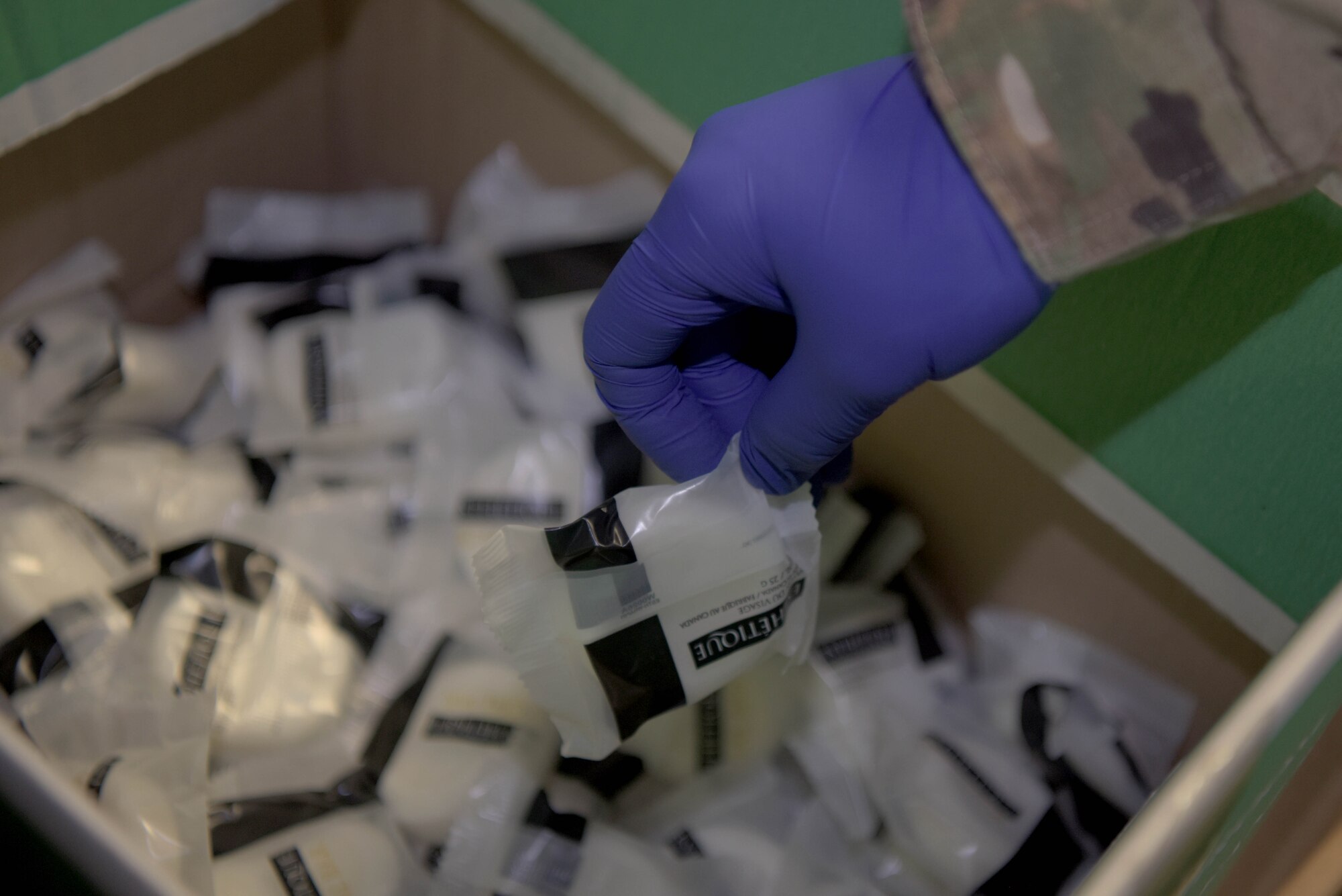 Staff Sgt. Adam Copp, 100th Force Support Squadron sports director, picks up a bar of soap while putting together a kit of essentials for transient Airmen at RAF Mildenhall, April 22, 2020. Large amounts of supplies such as linen, blankets, pillows and toiletries were needed to accommodate the transient Airmen. (U.S. Air Force photo by Senior Airman Benjamin Cooper)