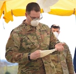 Pvt. Jerimya Stoner, lane decontamination specialist with Delta Company, 1st Battalion, 109th Infantry Regiment, Pennsylvania National Guard, removes his gloves while in the decontamination tent at the COVID-19 testing site at Mohegan Sun Arena in Wilkes-Barre, Pa., April 20, 2020.