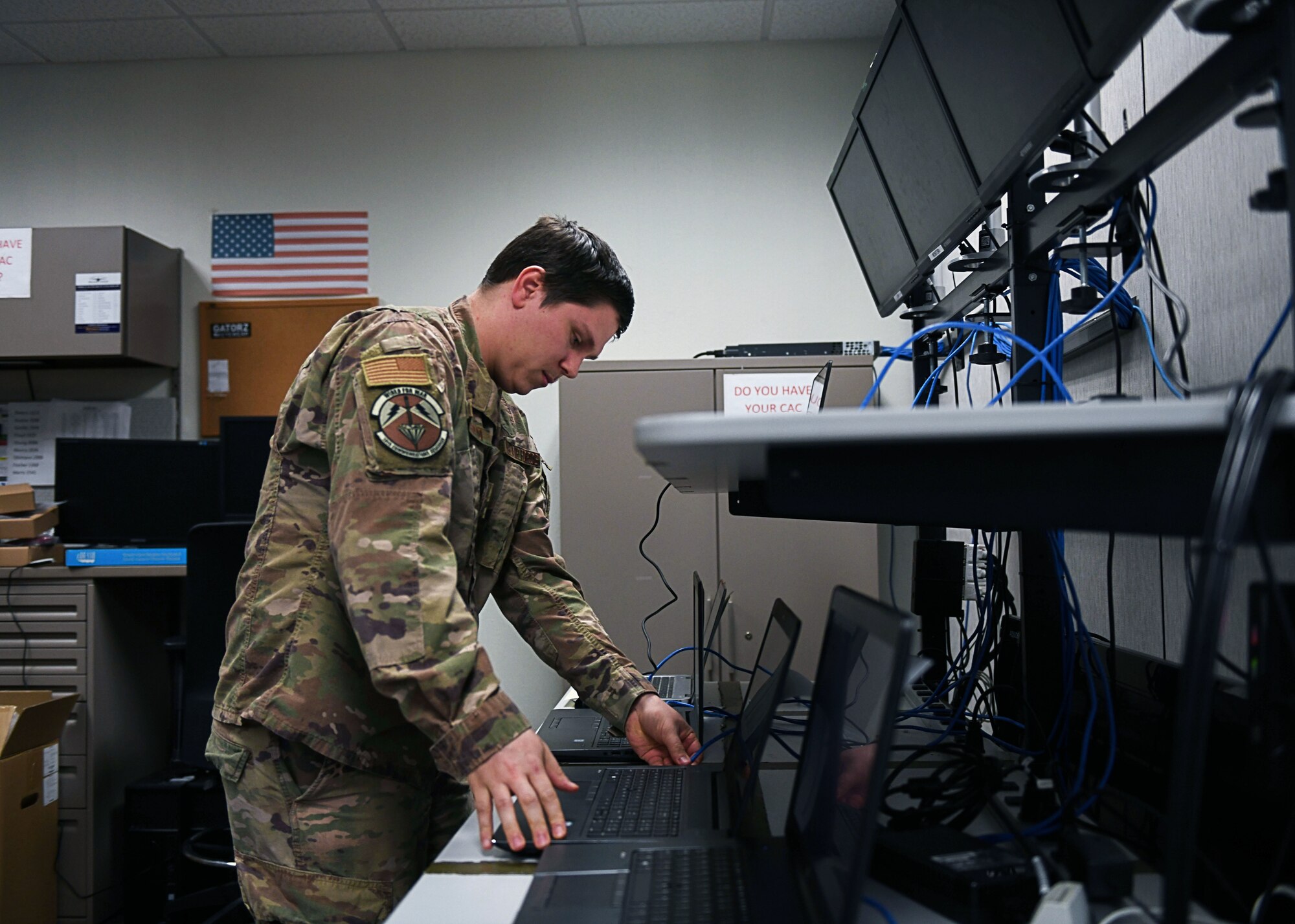 An Airman stands over a desk.