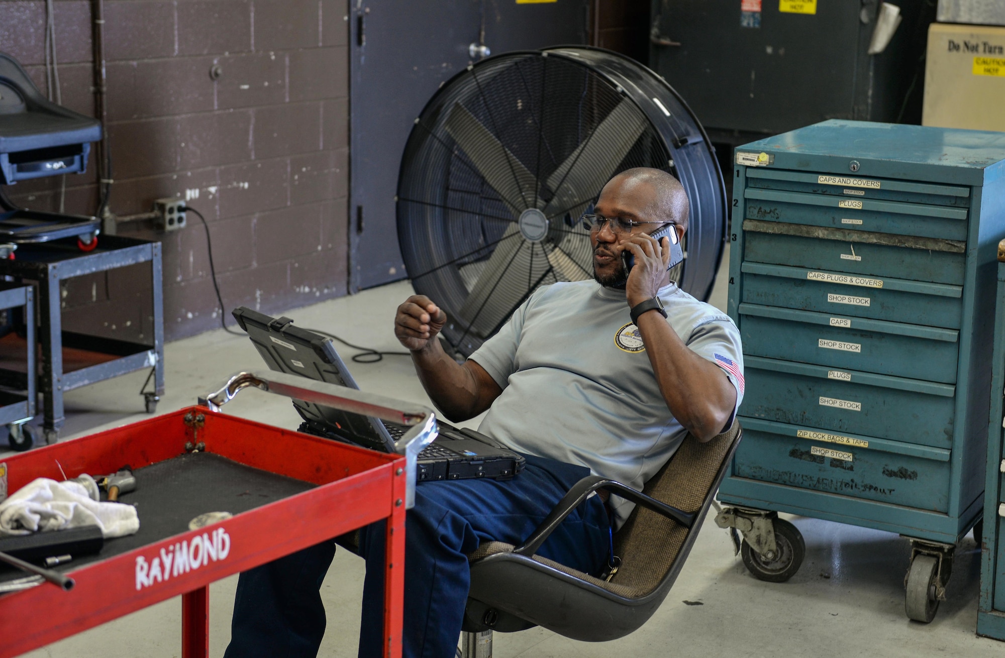Rodney Williams, M1 Support Services lead propulsion mechanic, teleworks with a co-worker April 17, 2020, at Columbus Air Force Base, Miss. According to the CDC, individuals should practice social distancing by teleworking as much as possible. (U.S. Air Force photo by Airman 1st Class Davis Donaldson)