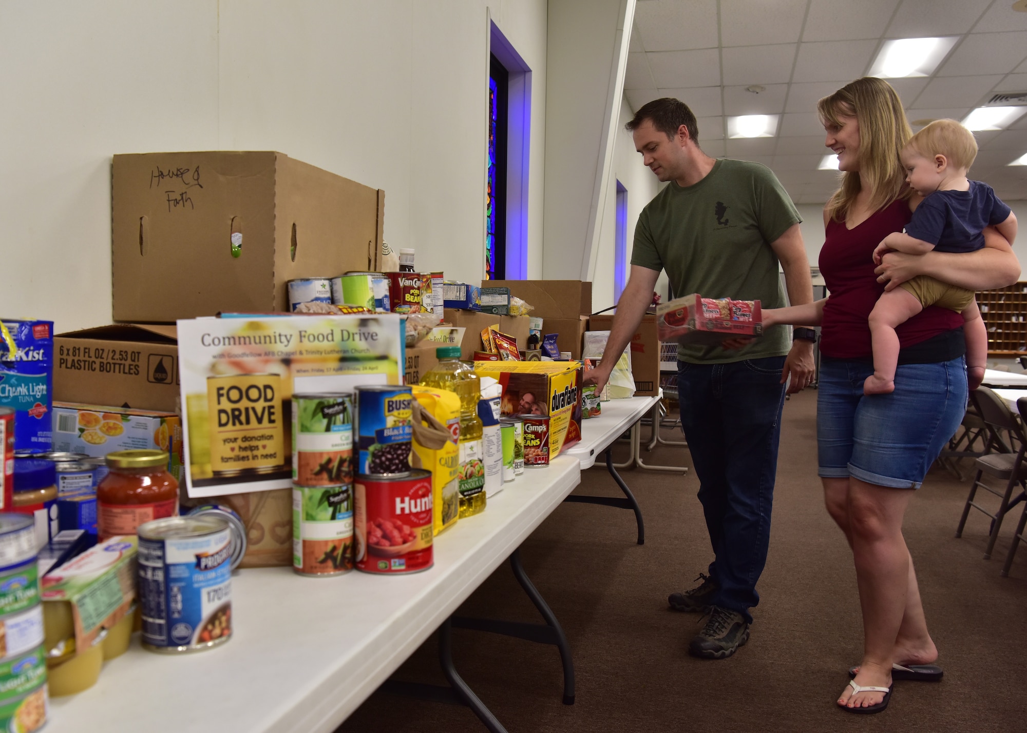 U.S. Air Force Capt. Jonathan Shour, 17th Training Wing chaplain, along with his wife Rebecca and son Ezekiel, organize donations during a food drive at Trinity Lutheran Church in San Angelo, Texas, April 22, 2020. The church is one of the locations collecting donations from Goodfellow Air Force Base members and the local community and continues until April 24. (U.S. Air Force photo by Staff Sgt. Chad Warren)