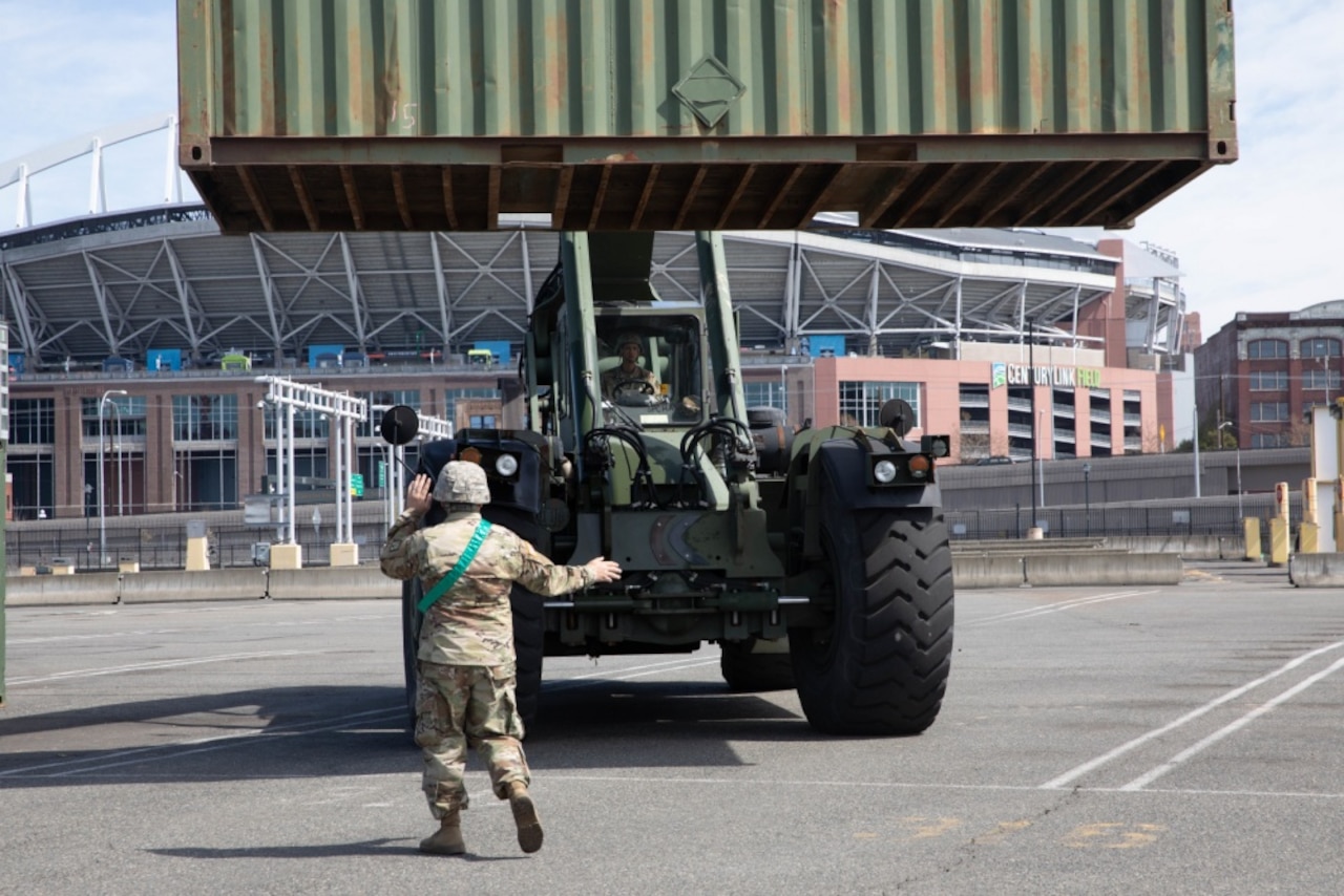 A soldier directs a forklift.