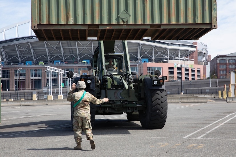 A soldier directs a forklift.