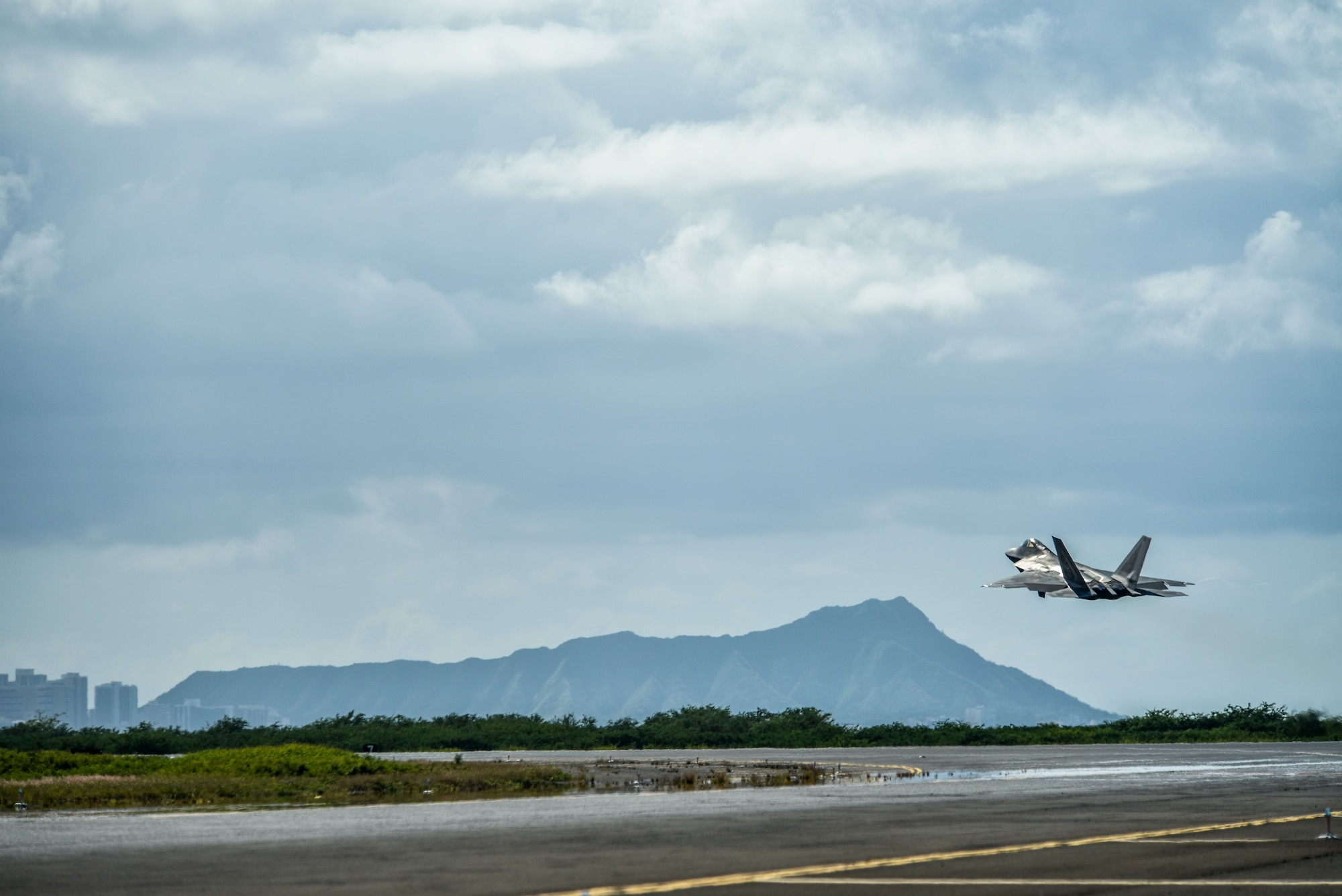 A U.S. Air Force F-22 Raptor takes off from the runway during a routine training schedule April 21, 2020, at Honolulu International Airport, Hawaii. Given the low traffic at the airport due to COVID-19 mitigation efforts, the active-duty 15th Wing and the Hawaii Air National Guard’s 154th Wing seized an opportunity to document the operation which showcases readiness and their unique Total Force Integration construct. The units of Team Hickam work together seamlessly to deliver combat airpower, tanker fuel, and humanitarian support and disaster relief across the Indo-Pacific. (U.S. Air Force photo by Tech. Sgt. Anthony Nelson Jr.)