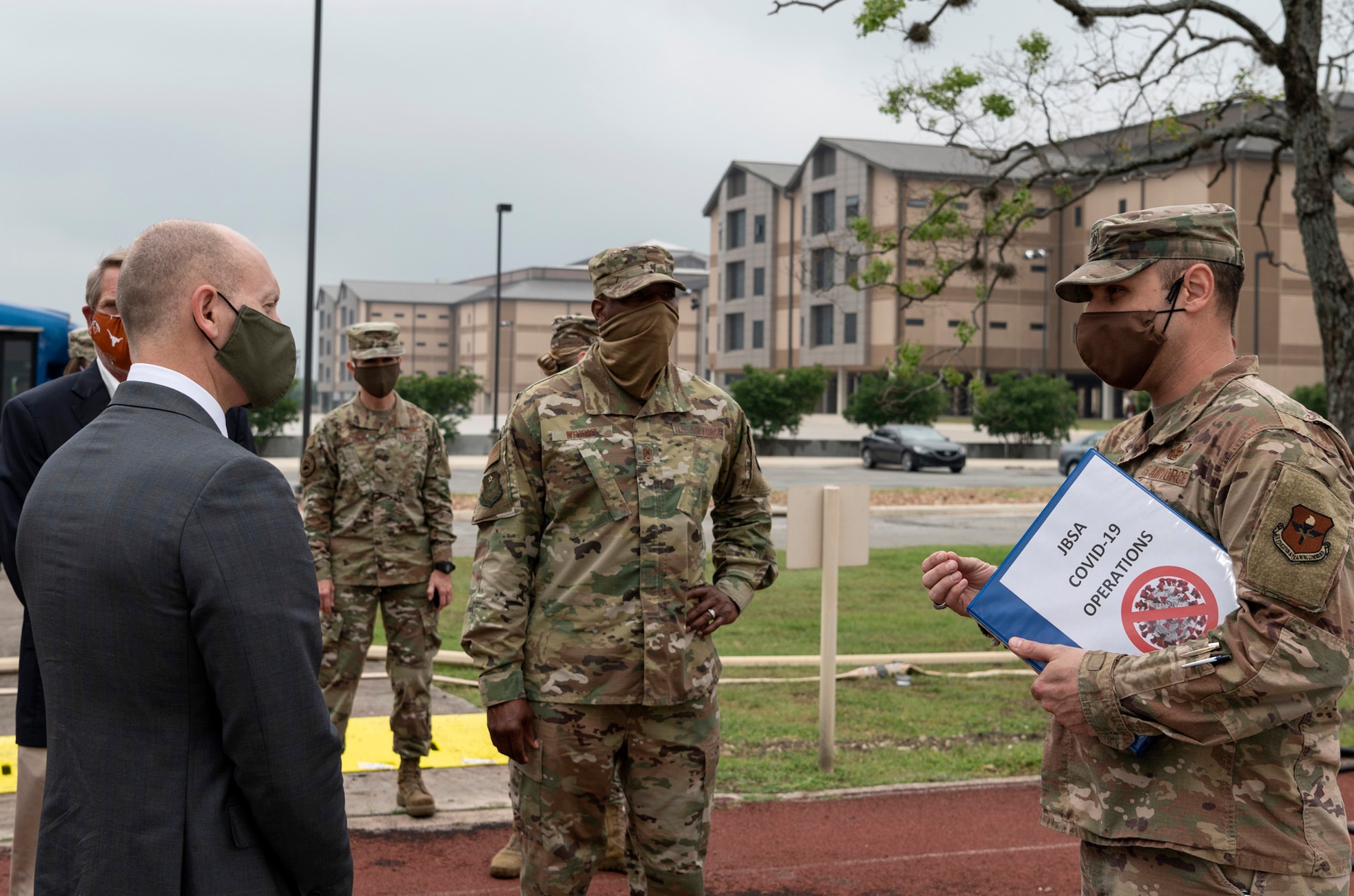 indviduals listen to a briefing outside on a track