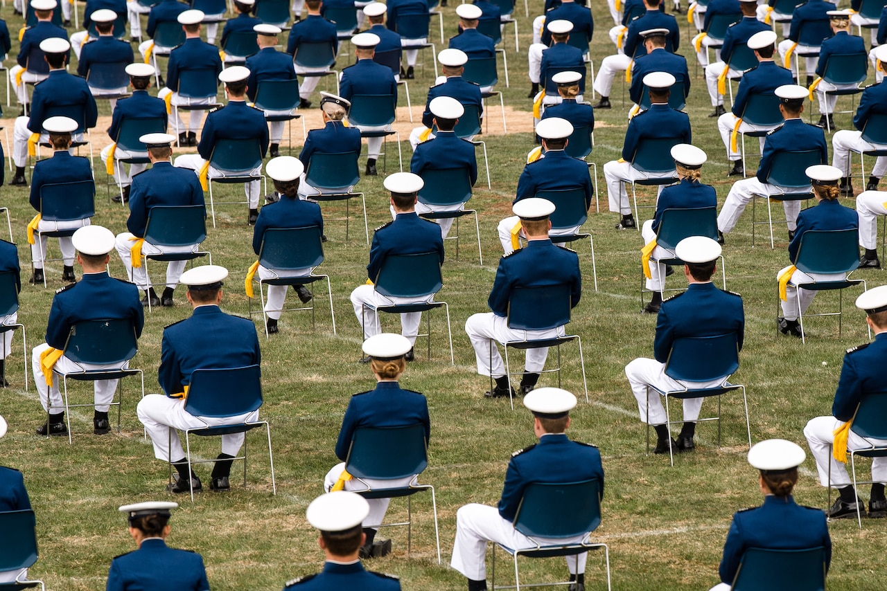 Cadets in dress uniform and cap, sit in lawn chairs spaced 6 feet in each direction.