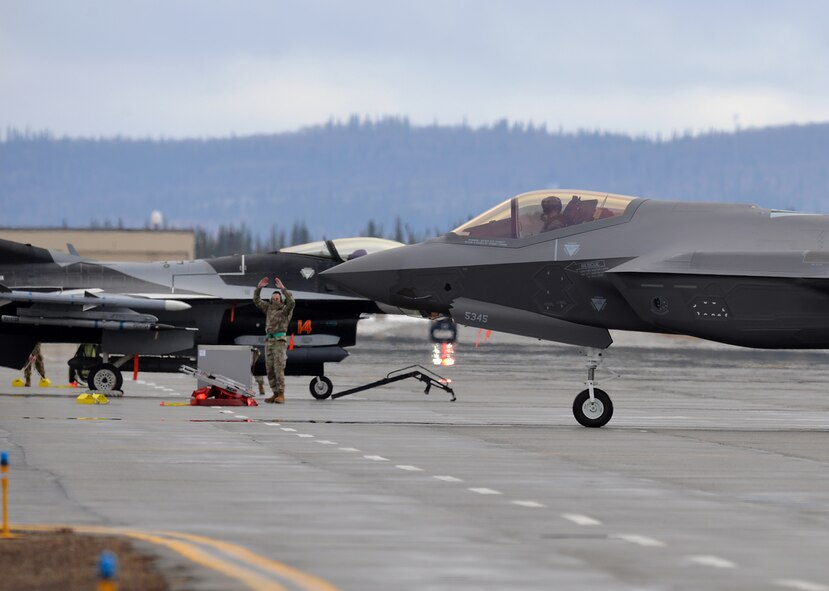 U.S. Air Force Lt. Col. James Christensen, the 356th Fighter Squadron (FS) commander, takes direction from Staff Sgt. Christopher Mashek, a 356th Aircraft Maintenance Unit (AMU) F-35 dedicated crew chief, as he is marsheled in after bringing one of the first two F-35A Lightning II fifth-generation aircraft to Eielson Air Force Base, Alaska, April 21, 2020.