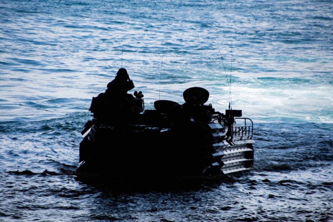 Marines travel in an amphibious assault vehicle moving through water.