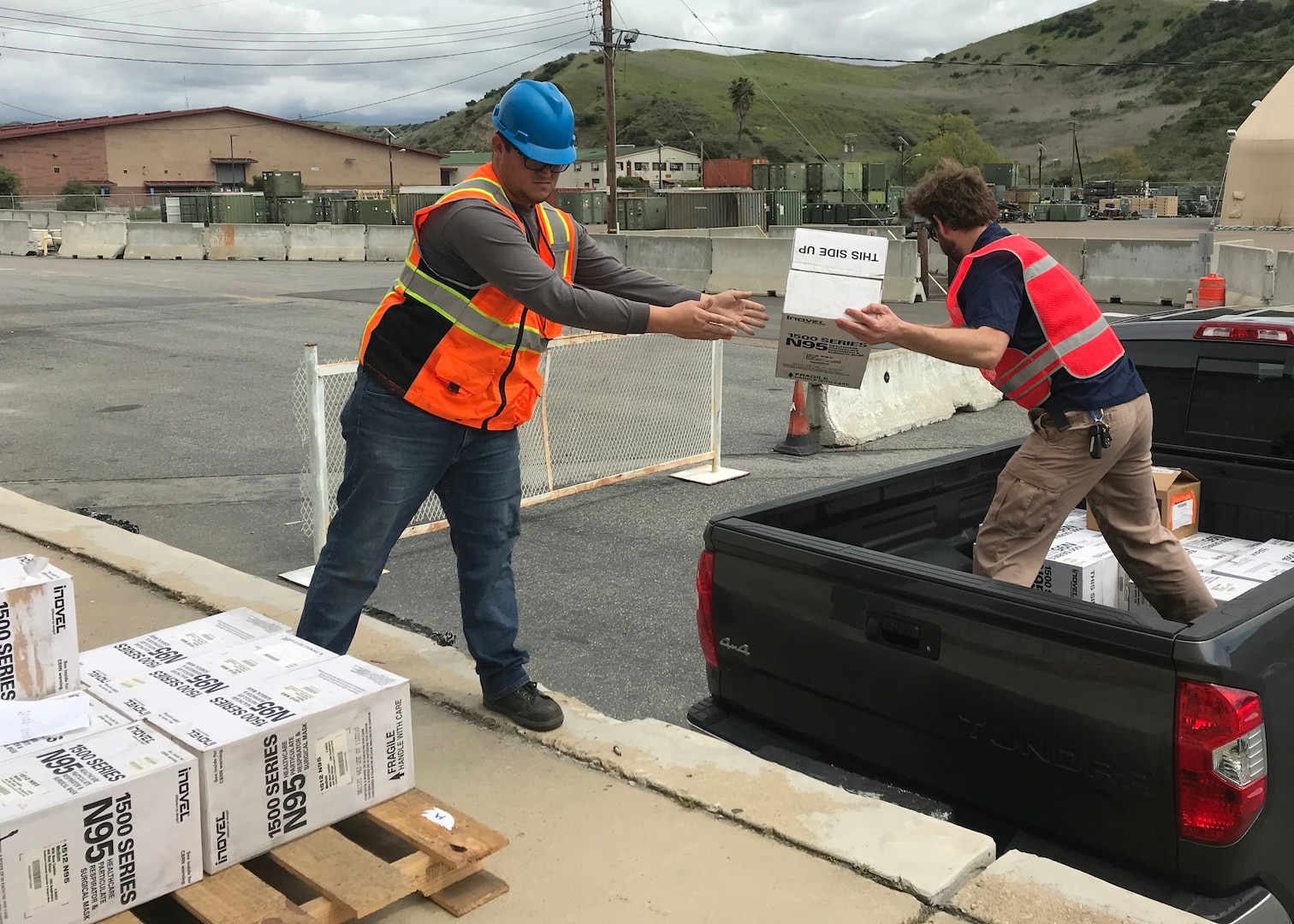 Two men load boxes into a pickup truck