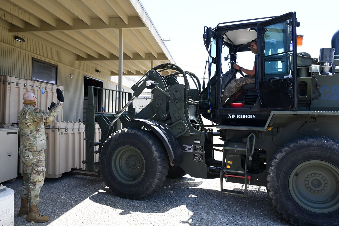 A member of the 30th Civil Engineer Squadron, guides Airman 1st Class Chance Pickell, 30th Logistics Readiness Squadron ground transportation operator, as he picks up a container April 22, 2020, at Vandenberg Air Force Base, Calif.
