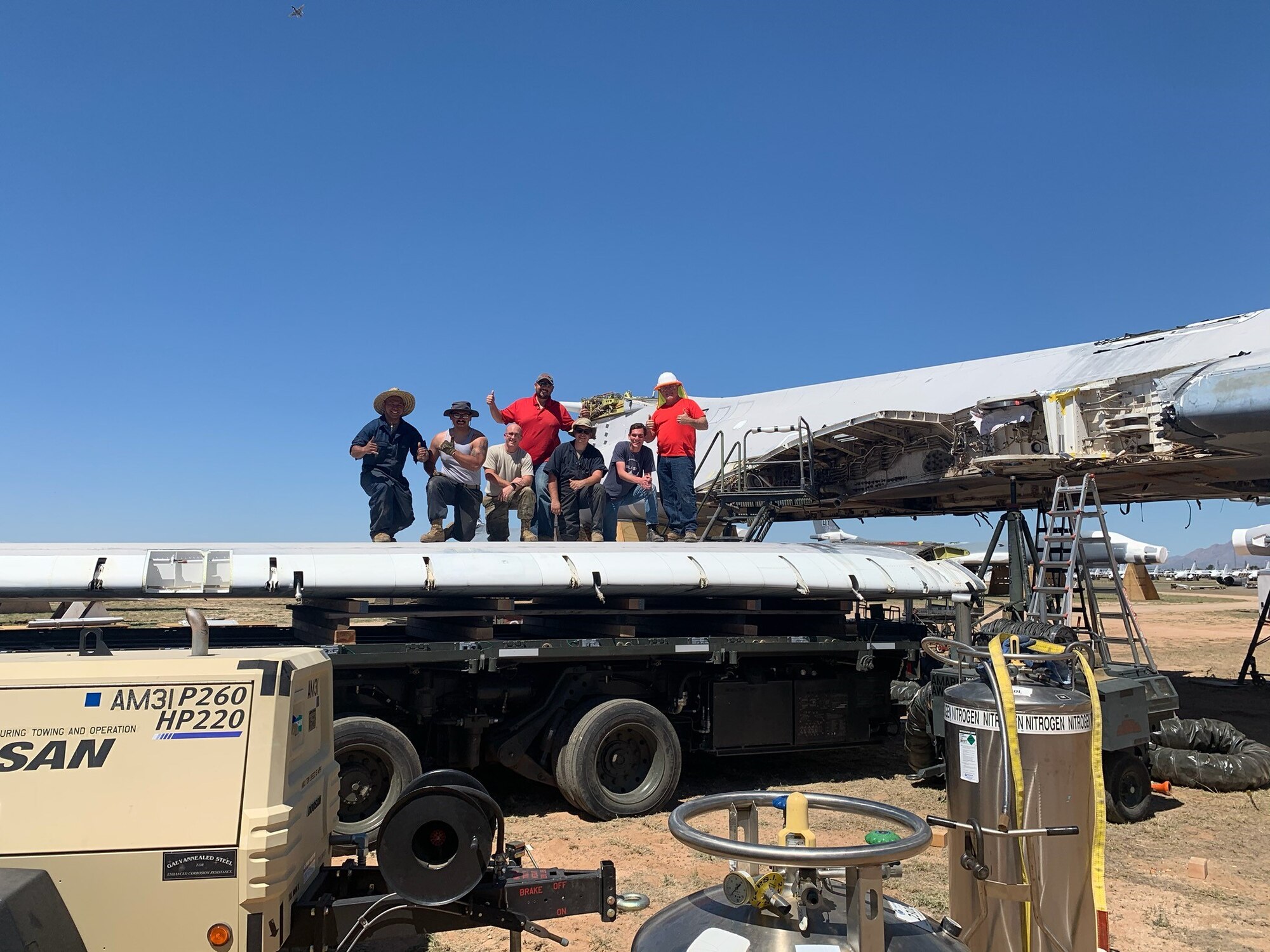 The crew stands atop the wing they just removed from tail 85-0092 to make it ready for transportation.