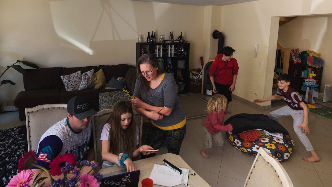 U.S. Army Sgt. 1st Class Cody Camp, left, U.S. Army Recruiting Command senior guidance counselor and his wife, Beth, center, assist their daughter with her classwork and as their other children play at their home in Kaiserslautern, Germany