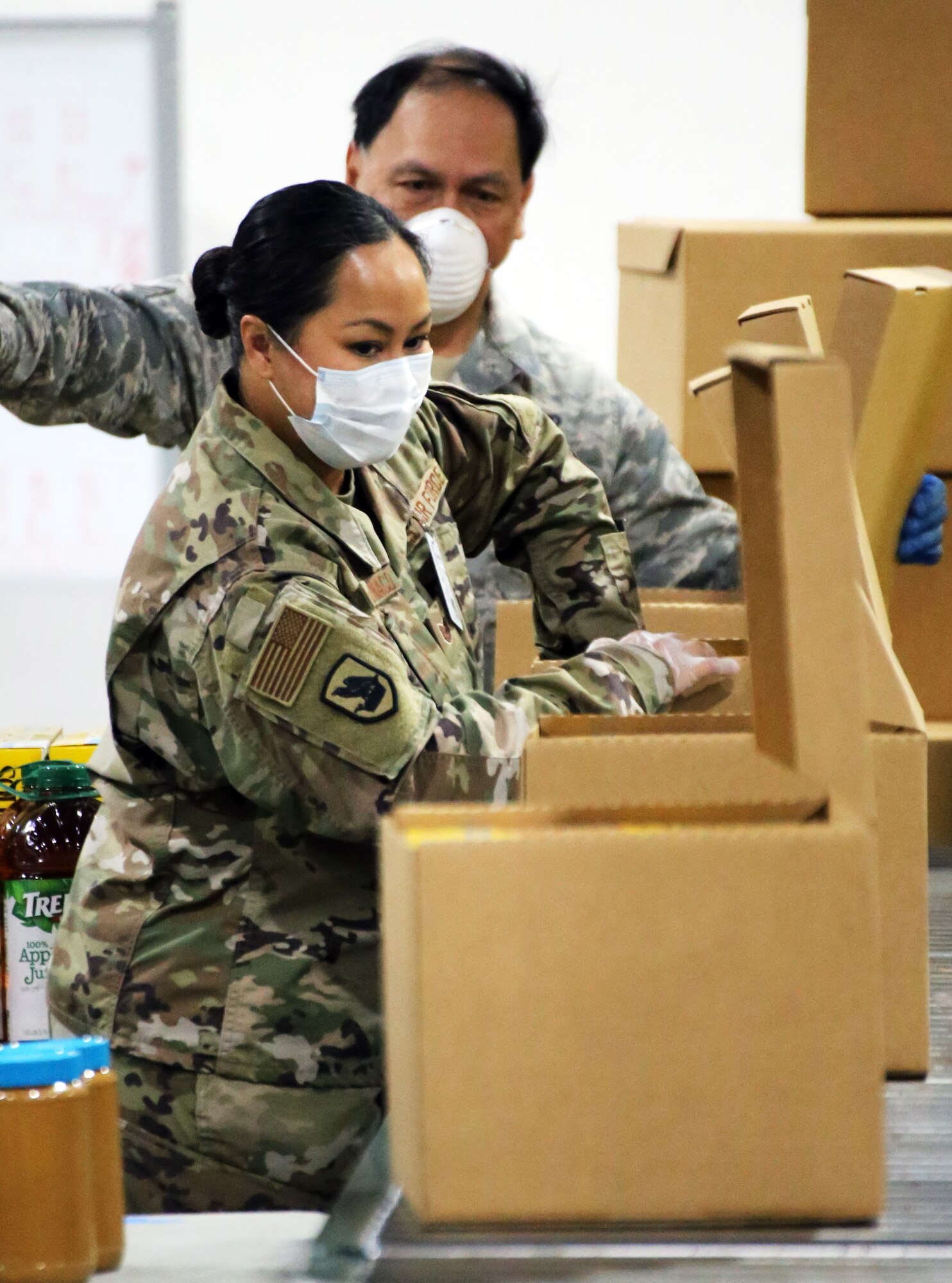 Members of the Washington Air National Guard closes an emergency food box packed at the Food Lifeline temporary site in Seattle, Wash. on April 21, 2020. Members of the Washington Air and Army National Guard are supporting food banks around the state during the COVID-19 pandemic response. (U.S. National Guard photo by Joseph Siemandel)