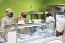 Senior Airman Jeremiah Jackson and Senior Airman Amanda Miller, food service journeymen assigned to the 628th Force Support Squadron, take a customer's order at the Gaylor Dining Facility at Joint Base Charleston, S.C., April 22, 2020. Dining facility personnel are cleaning more often, wearing masks and gloves and practicing physical distancing in order to protect themselves and customers. The DFAC is currently open for carry out only.