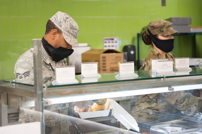 Senior Airman Jeremiah Jackson and Senior Airman Amanda Miller, food service journeymen assigned to the 628th Force Support Squadron, prepare food at the Gaylor Dining Facility at Joint Base Charleston, S.C., April 22, 2020. Dining facility personnel are cleaning more often, wearing masks and gloves and practicing physical distancing in order to protect themselves and customers. The DFAC is currently open for carry out only.
