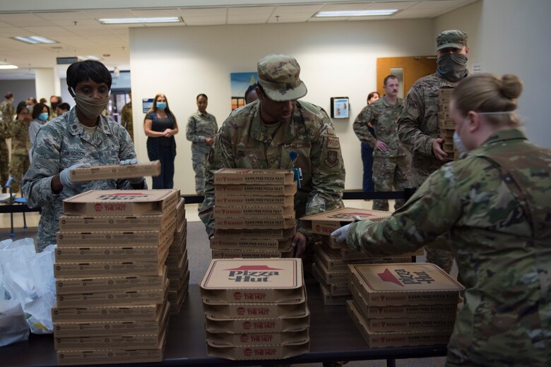 Major Michelle Law-Gordon, 628th Air Base Wing senior installation chaplain, and Master Sgt. Jennifer Deprinzio, 628th Air Base Wing superintendent of religious affairs, prepare to pass out food at the 628th Medical Group at Joint Base Charleston, S.C. April 22, 2020. JB Charleston chaplains passed out pizza and sandwiches to raise morale and thank Medical Group personnel for all their hard work during the COVID-19 pandemic. The chaplains wore masks and gloves to protect the Airmen they handed food to.