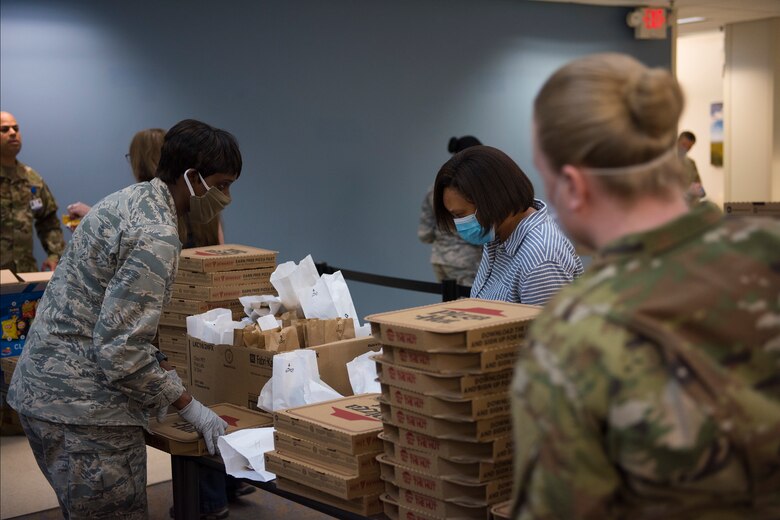 Major Michelle Law-Gordon, 628th Air Base Wing senior installation chaplain, and Master Sgt. Jennifer Deprinzio, 628th Air Base Wings superintendent of religious affairs, pass out food at the 628th Medical Group at Joint Base Charleston, S.C. April 22, 2020. JB Charleston chaplains passed out pizza and sandwiches to raise morale and thank Medical Group personnel for all their hard work during the COVID-19 pandemic. The chaplains wore masks and gloves to protect the Airmen they handed food to.