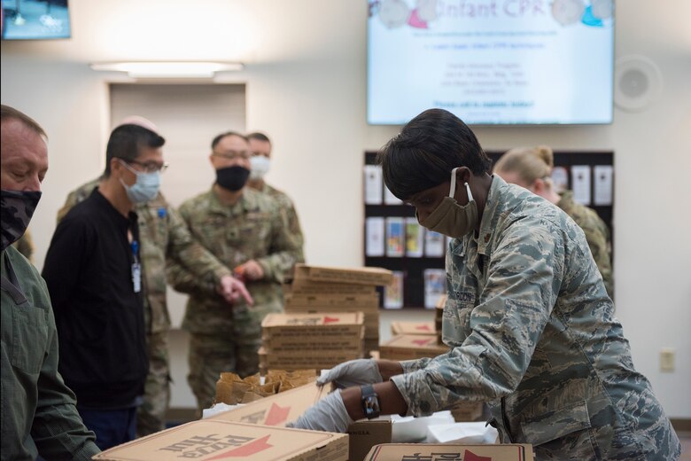 Major Michelle Law-Gordon, 628th Air Base Wing senior installation chaplain, passes out food at the 628th Medical Group at Joint Base Charleston, S.C. April 22, 2020. JB Charleston chaplains passed out pizza and sandwiches to raise morale and thank Medical Group personnel for all their hard work during the COVID-19 pandemic. The chaplains wore masks and gloves to protect the Airmen they handed food to.