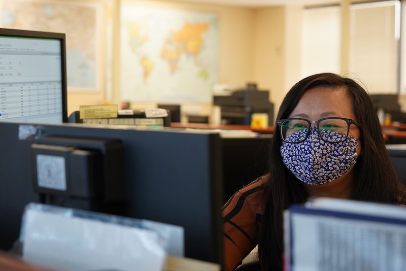 A woman wearing a mask looks at the camera.