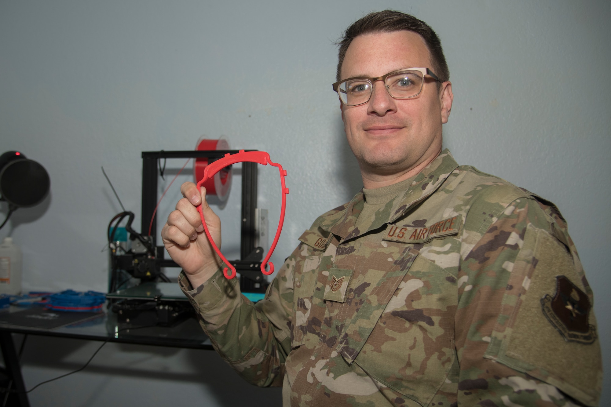 Tech. Sgt. Kyle Good, 54th Operations Support Squadron and White Sands Missile Range Air Traffic Control watch supervisor, holds a 3-D printer face-shield frame at the residence of his fellow 3-D printing partner, Staff Sgt. Jakob Powers, in Alamogordo, N.M., on April 16, 2020. The duo can currently print two face-shield frames in two hours per printer. (U.S. Air Force photo by Senior Airman Collette Brooks)