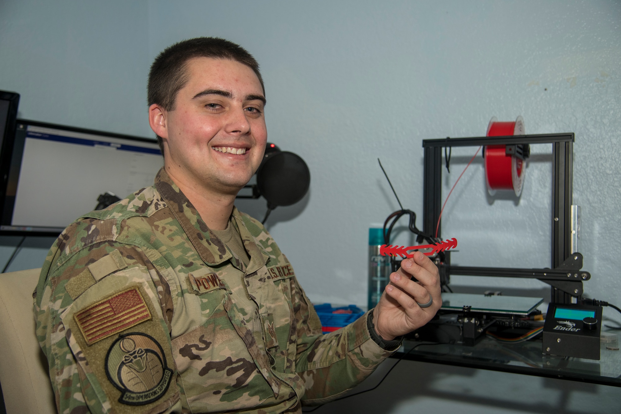 Staff Sgt. Jakob Powers, 54th Operations Squadron air traffic controller, holds a 3-D printed face-covering extender at his residence in Alamogordo, N.M., on April 16, 2020. With the combined efforts of Powers and his 3-D printing enthusiast partners, Tech. Sgt. Kyle Good, 54th Operations Support Squadron and White Sands Missile Range Air Traffic Control watch supervisor and his wife, Jamie Good, Staff Sgt. Jakob Powers and his wife, Staff Sgt. Kaitlyn Powers; both 54th OSS air traffic controllers, they are equipped to print 250 face-covering extenders a day. These coverings are aiding essential personnel in their ability to wear surgical face-coverings while maintaining comfort behind their ears. (U.S. Air Force photo by Senior Airman Collette Brooks)