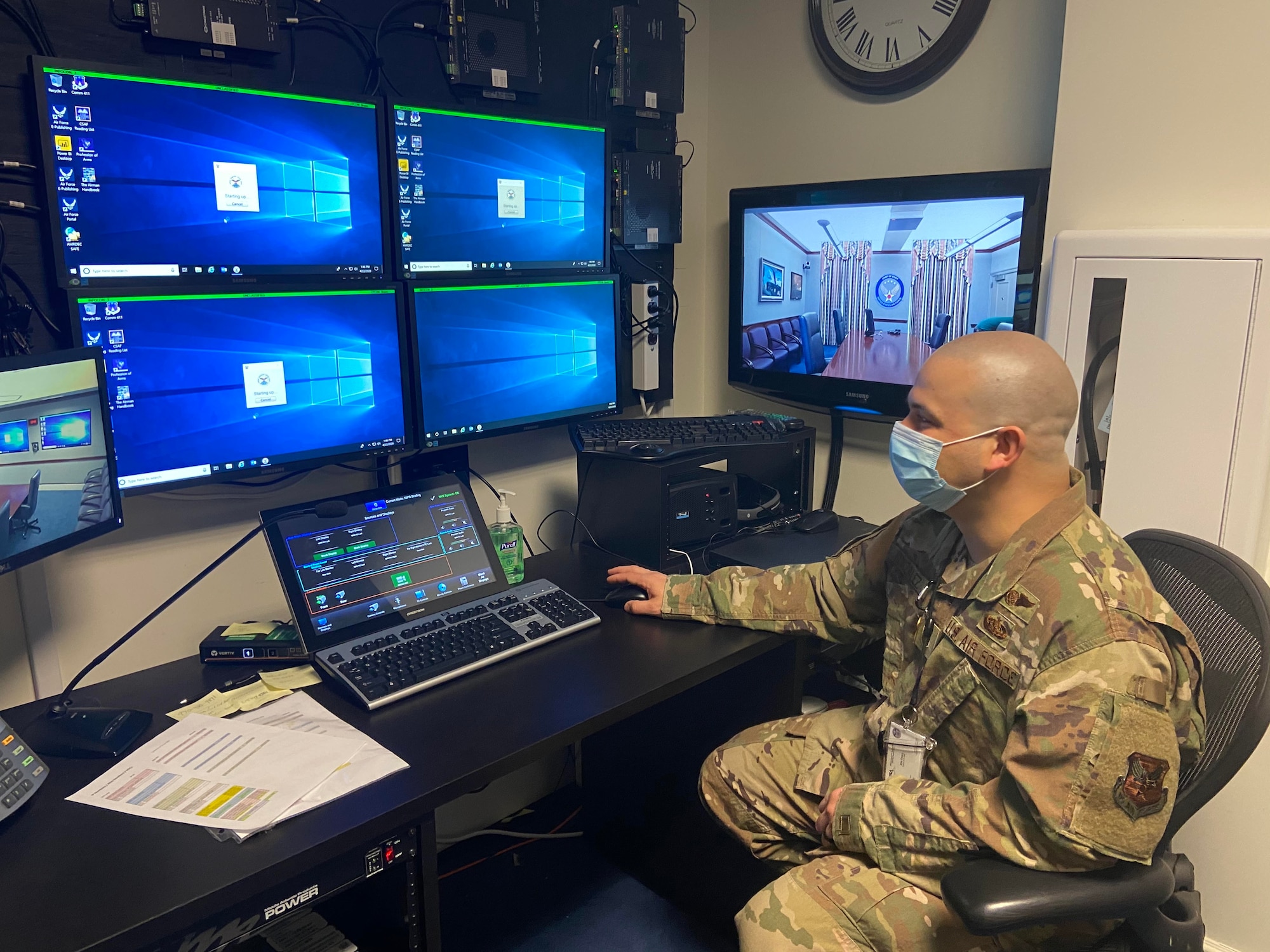 Airman sits a computer while wearing a mask.