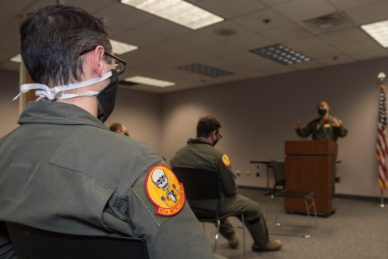 service members listen to a briefing wearing cloth masks and social distancing.