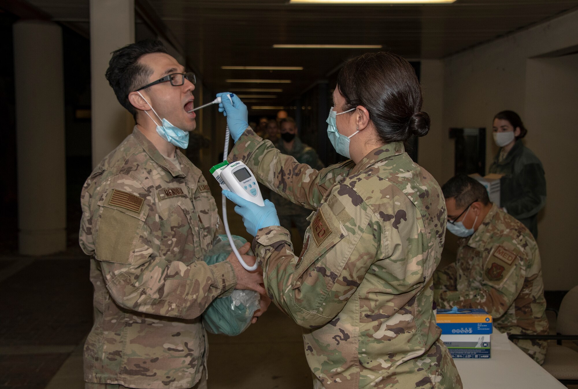 U.S. Air Force Tech. Sgt. Lisa Gonzales-Marin, right, 349th Aerospace Medicine Squadron medical service craftsman, takes the temperature of Capt. Isaac Mendoza, left, 349th AMDS critical care nurse, prior to deployment April 22, 2020, at Travis Air Force Base, California. Medical staff from the 349th Medical Group deployed to New York in support of a short-notice COVID-19 mission. (U.S. Air Force photo by Heide Couch)